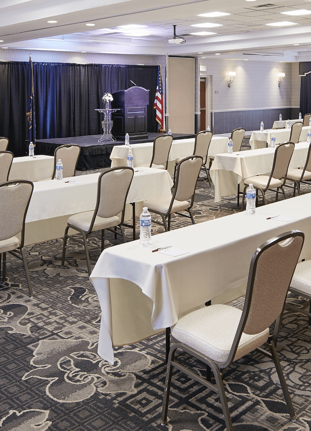 Conference room in the Best Western Plus Abbey Inn. Shows three rows of tables with seats facing a curtained stage